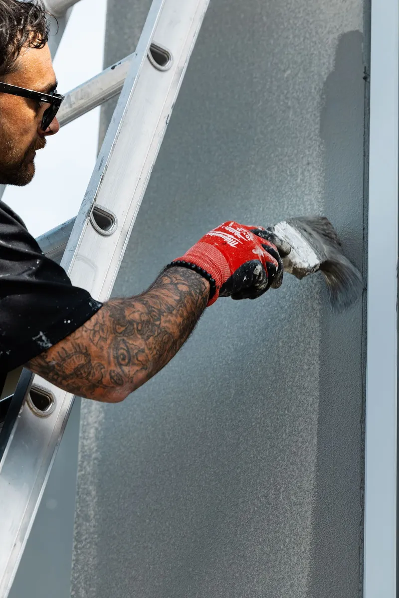 Platinum Painting crew member inspecting a freshly painted weatherboard wall