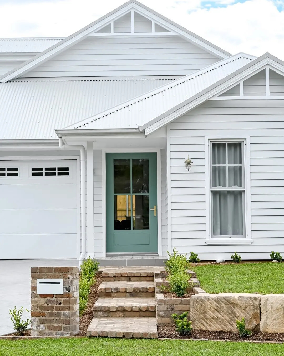 White weatherboard cottage with a teal front door, freshly repainted